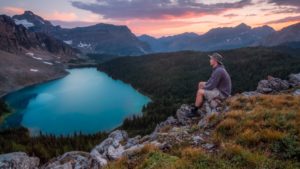 A man sitting on rocks and taking in the beauty around him because IV ketamine infusions restore his power to enjoy a moment.