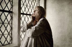 Old woman in ancient asylum suffers alone, because psychiatric disorders were misunderstood, showing the stigmatizing term: mentally ill is no longer relevant.