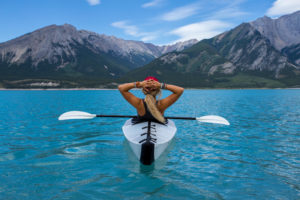 Woman in a kayak in a beautiful lake sits back and enjoys the view after IV ketamine relieved her treatment-resistant depression.