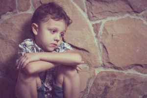 Child sits alone listless, depressed.