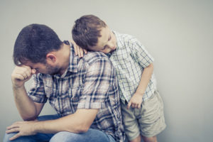 Little boy hugs his depressed dad. Does depression run families?