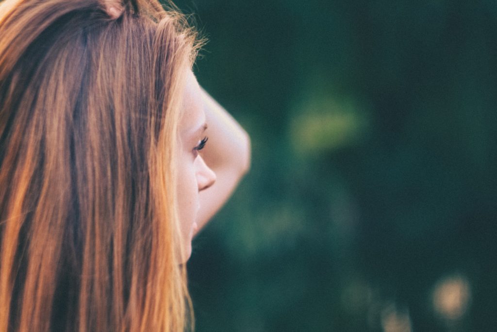 Young woman holds her hair back while she thinks about the pain and marginalizing of stigma.