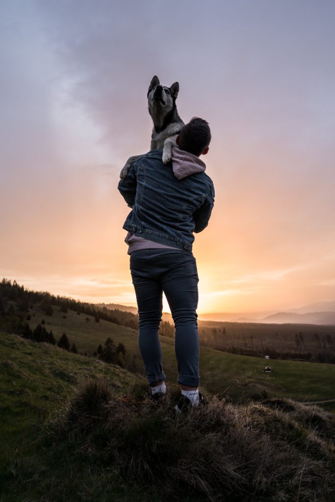 As this man carries his exhausted dog, he enjoys the glow of sunset.